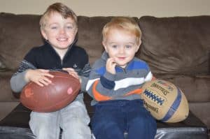 two kids with two footballs they received as christmas gifts