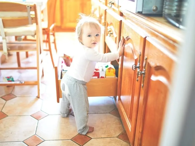 Childproofing and toddler proofing your home featured image of a toddler opening a cabinet