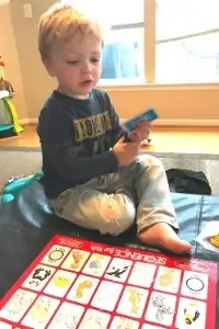 a three year old holding cards and playing the Sequence board game