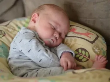 Baby lying on a boppy while mom is pumping