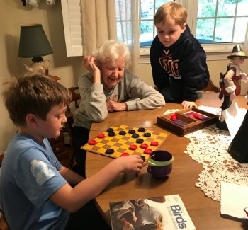 Great grandmother and great grandchildren playing checkers